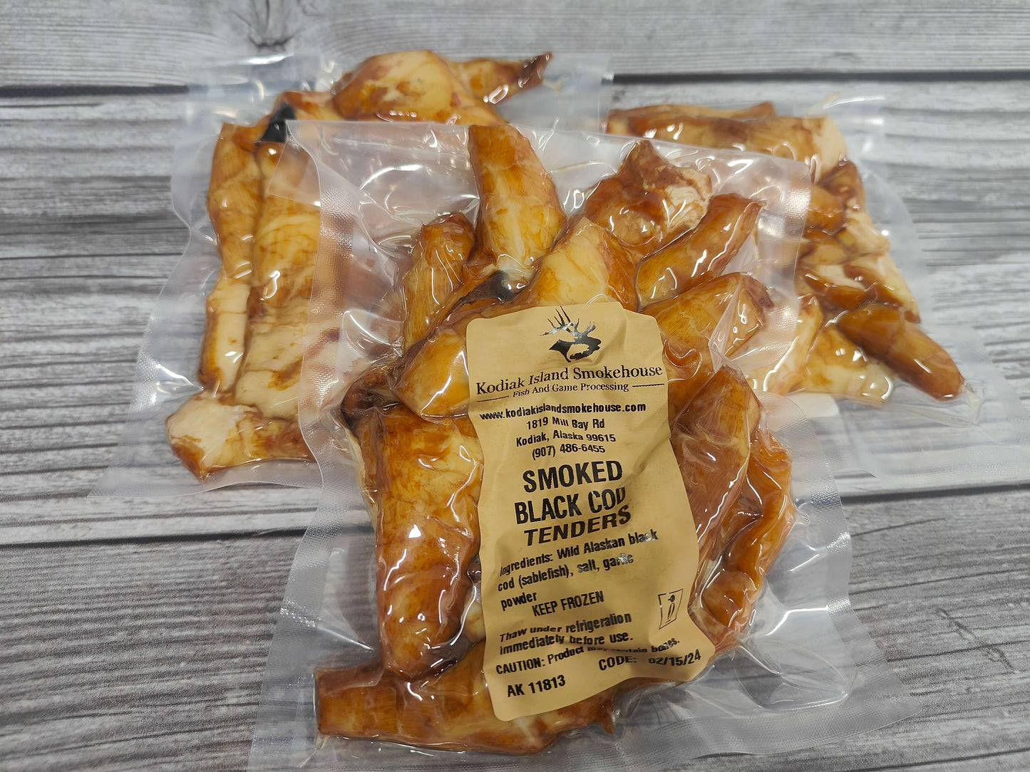 Packaged smoked black cod tenders with a label on a wooden surface