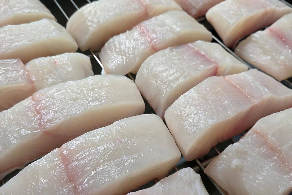 Wild Alaska halibut portions hand-cut and arranged on a processing rack at Kodiak Island Smokehouse.