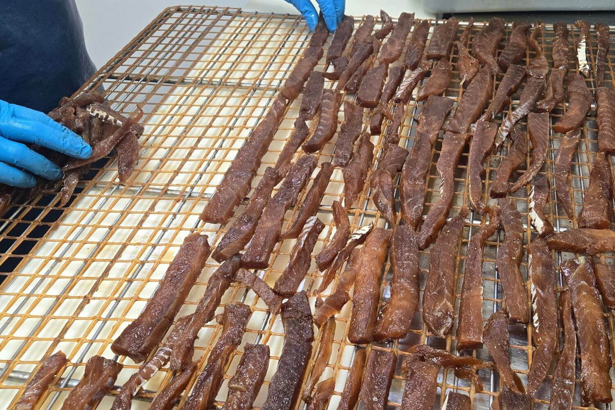 Wild Alaska fish jerky strips laid out by hand on drying racks at Kodiak Island Smokehouse.