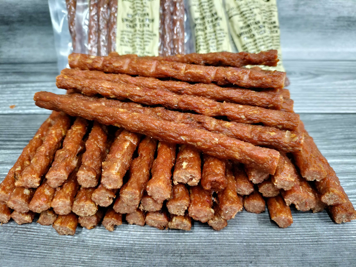 Wild Alaskan smoked salmon snack sticks stacked on rustic wood surface.