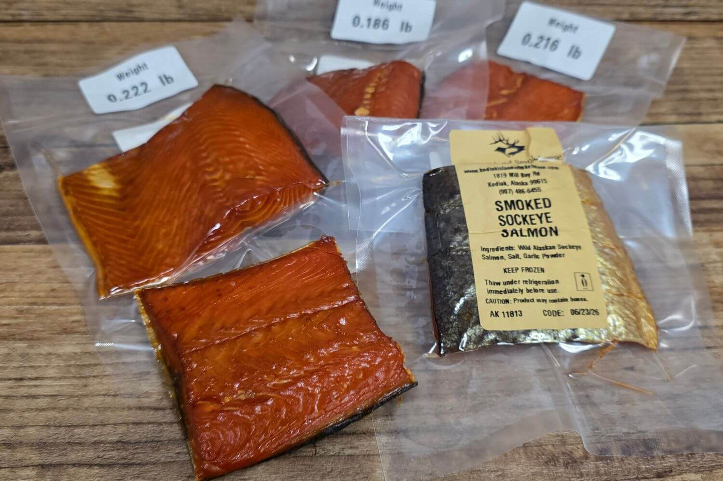 Individually vacuum-sealed wild Alaskan smoked salmon snack pieces on a rustic wooden surface