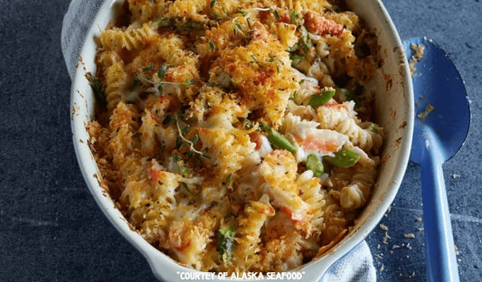 A baking dish of creamy Alaska crab fusilli pasta with asparagus and golden breadcrumbs, baked to perfection in a rich cheese sauce.