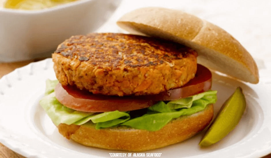 Grilled Alaska salmon burger on a toasted bun with lettuce and tomato.