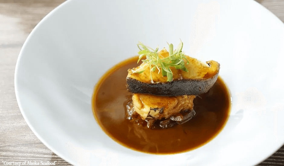 Braised Alaska sablefish served in a rich ginger-scallion sauce, garnished with fresh scallions in a white bowl — elegant seafood dinner.