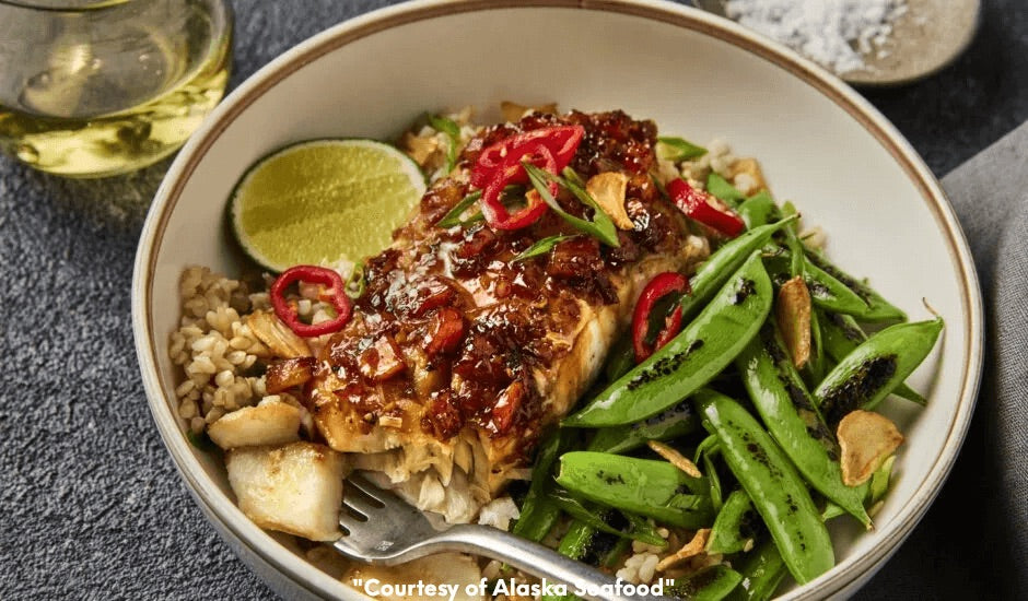 Bowl with wild Alaska rockfish fillet glazed in pineapple adobo sauce, served with brown rice, snap peas, and mixed greens, garnished with pineapple and sesame seeds.