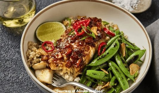 Bowl with wild Alaska rockfish fillet glazed in pineapple adobo sauce, served with brown rice, snap peas, and mixed greens, garnished with pineapple and sesame seeds.
