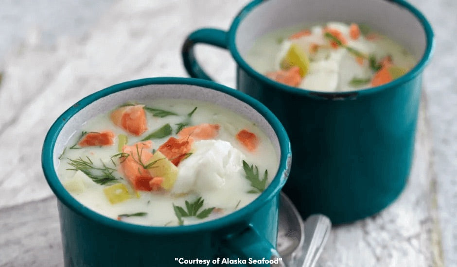 Bowl of creamy chowder filled with chunks of Alaska cod, flakes of smoked salmon, potatoes, and herbs, served warm.