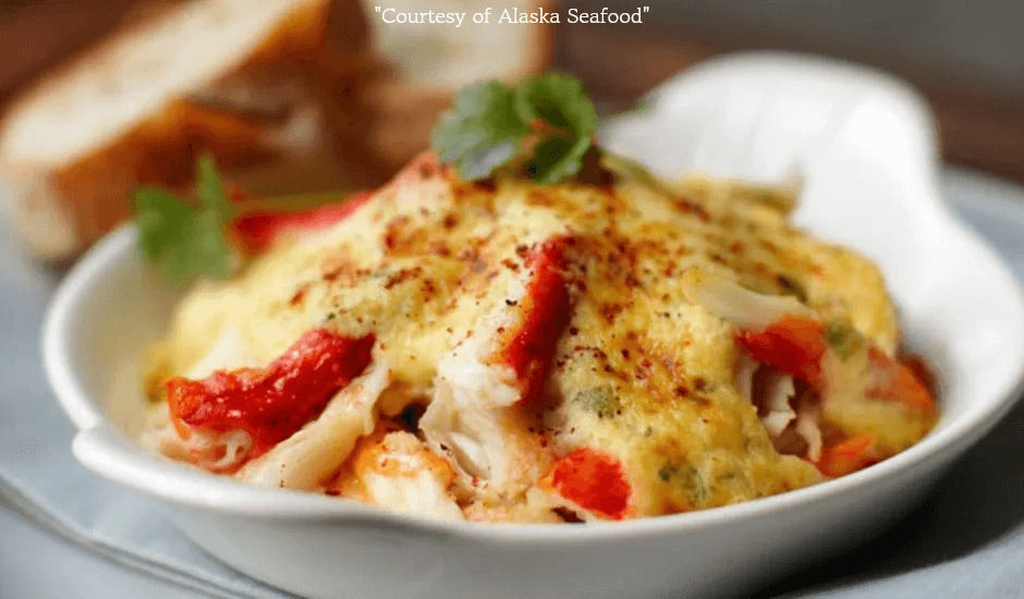 A broiled Alaska king crab leg topped with creamy lemon-cilantro sabayon, served hot with fresh herbs and a golden finish.