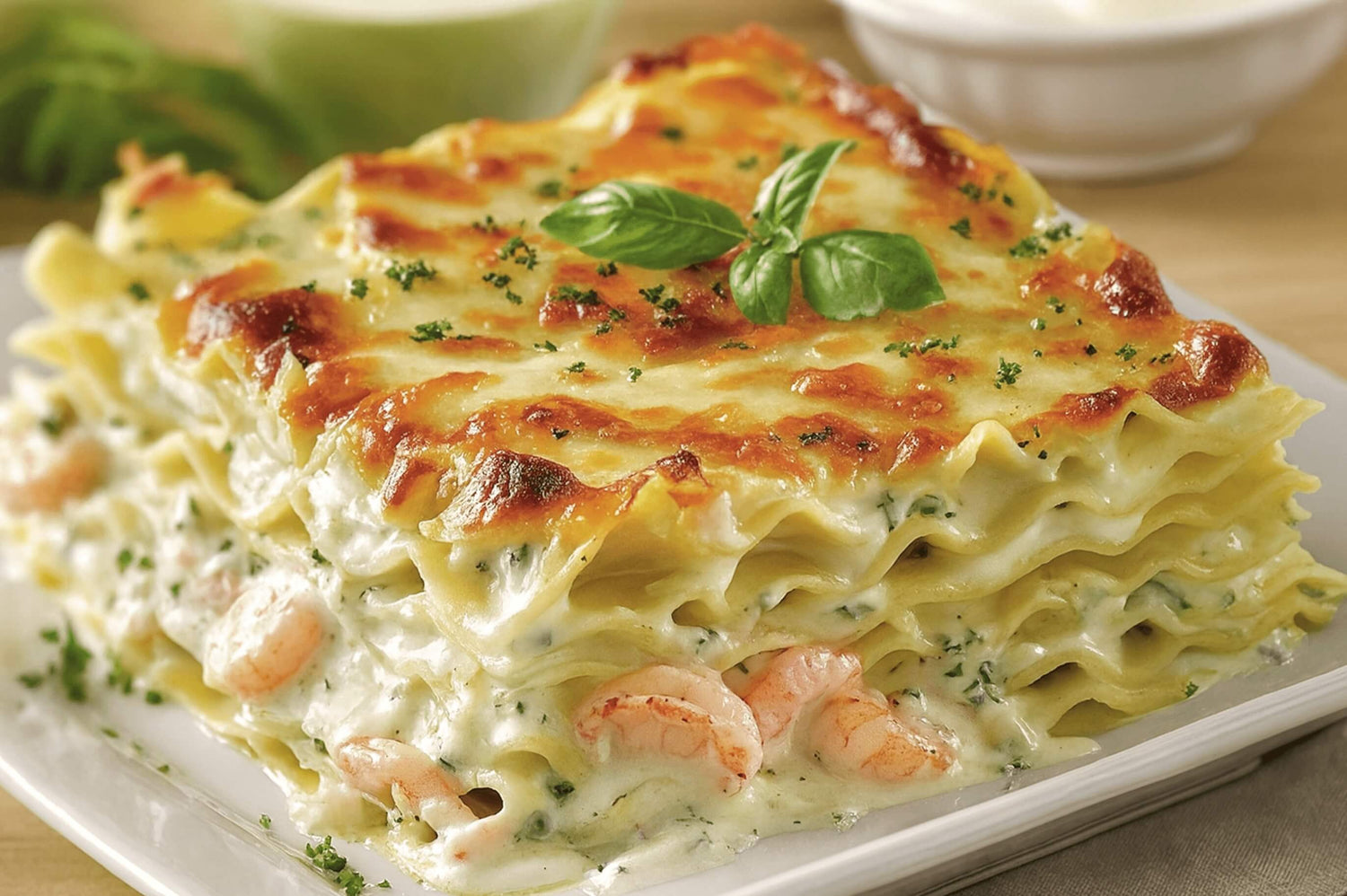 Seafood lasagna layered with halibut, shrimp, and creamy cheese sauce — golden baked and topped with herbs.