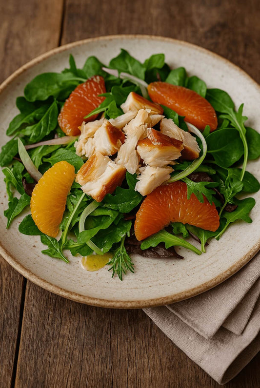 A salad featuring flaked smoked wild Alaska black cod, thinly sliced fennel, orange and grapefruit segments, and mixed baby greens drizzled with vinaigrette.