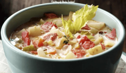 A creamy Alaska smoked salmon and chipotle chowder with chunks of salmon, potatoes, corn, and herbs, served in a rustic bowl with a garnish of fresh parsley.