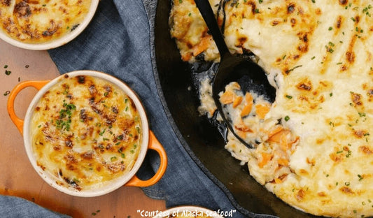 Alaska smoked salmon shepherd’s pie topped with golden mashed potatoes and celery root, garnished with fresh chives, served in a rustic baking dish.