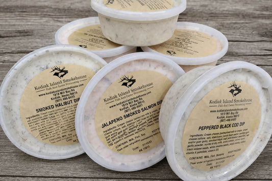 Six assorted smoked fish dips stacked on a rustic wooden background.