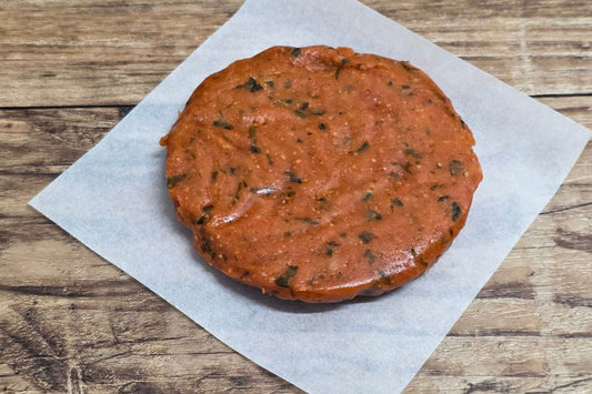 Grain-free Smoky Chipotle Wild Alaskan salmon burger patty on parchment over rustic wood.