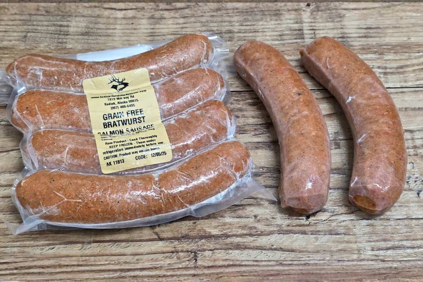 Wild Alaskan grain-free salmon bratwurst on rustic wood background, shown both vacuum-sealed and loose for a clear view of size and texture.
