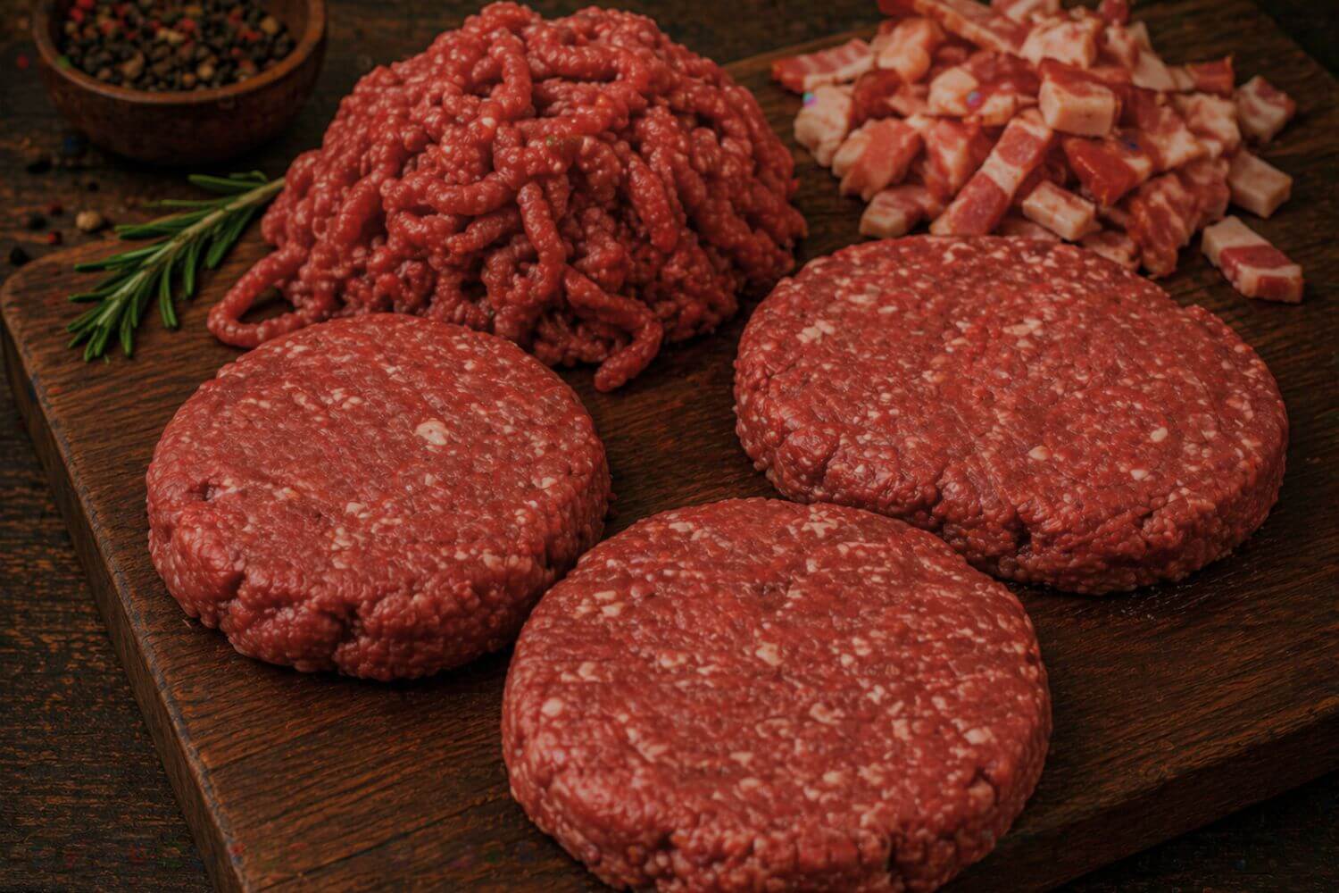 Wild game bacon burger patties with ground meat and diced bacon on a wooden board, ready for cooking