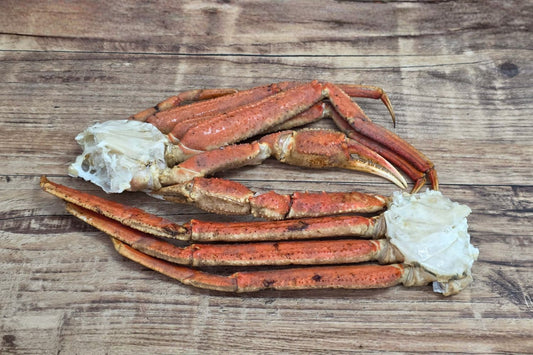 Wild Alaskan Bairdi crab cluster with intact legs and claws, fully cooked and displayed on rustic wood.