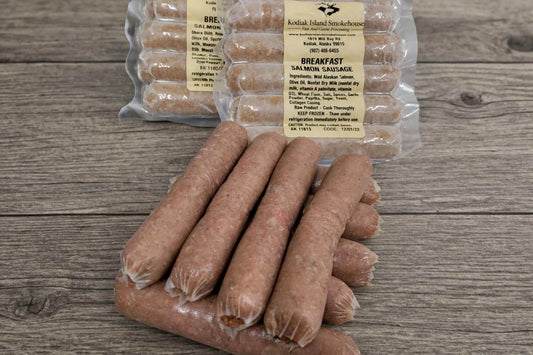 Vacuum-sealed packages of wild Alaskan salmon breakfast sausage links on a rustic wood surface.