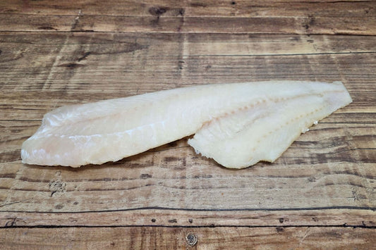 Wild Alaskan Pacific cod fillet on a rustic wood table, highlighting the mild white flesh typical of Kodiak-caught cod.