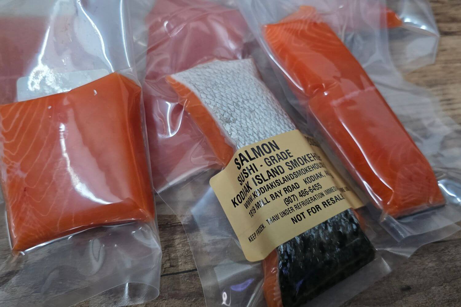 Packaged sushi-grade Alaskan salmon with a label on a wooden surface