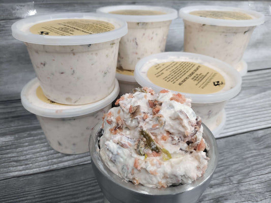 Containers of jalapeño smoked salmon dip with visible smoked salmon flakes and jalapeño pieces on a rustic wood surface.