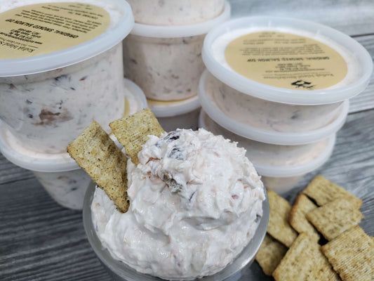 Smoked salmon dip in a container with visible salmon flakes and crackers.