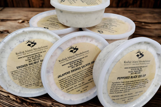 Six assorted smoked fish dips stacked on a rustic wooden background.