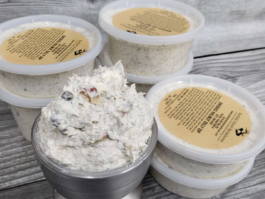 Containers of creamy smoked halibut dilly dip topped with dill and capers on a rustic wooden surface.