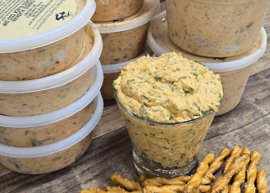 Containers of spicy smoked black cod dip with a bright, creamy texture on a rustic wooden surface.