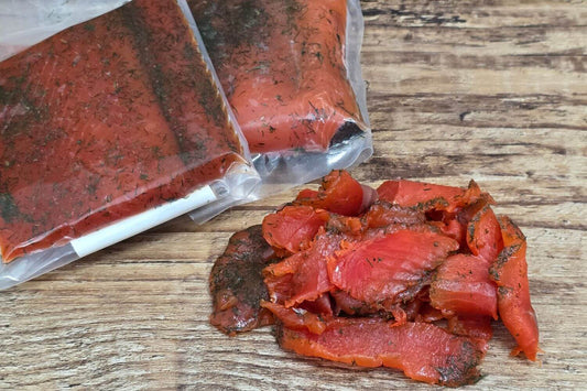 Vacuum-sealed Wild Alaskan salmon gravlax with sliced gravlax on a rustic wooden surface