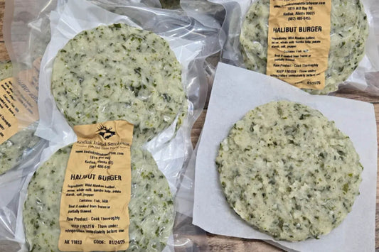 Vacuum sealed wild Alaskan halibut burger patties with visible green kelp flecks on a rustic wooden surface.