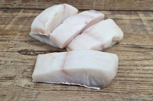 Raw Alaskan halibut portions arranged on a rustic wooden surface.