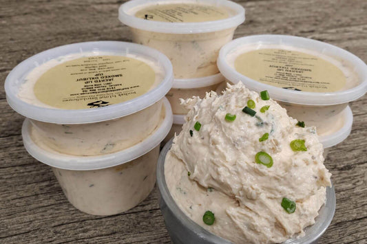 Containers of creamy smoked halibut dip topped with green onions on a rustic wooden surface.