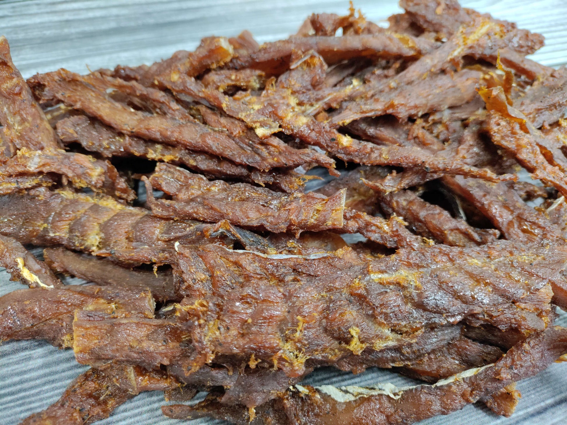 Sweet teriyaki-seasoned wild cod jerky strips on a wooden board.