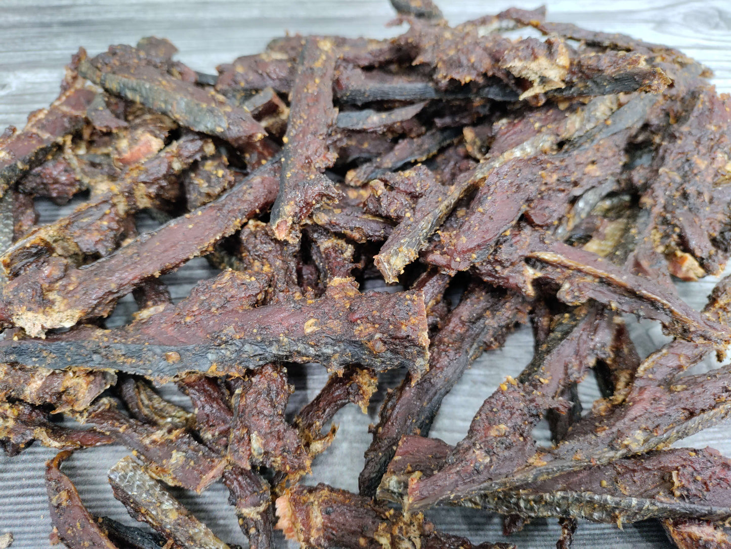 Smoked wild sockeye pepper jerky strips piled on a wooden board.
