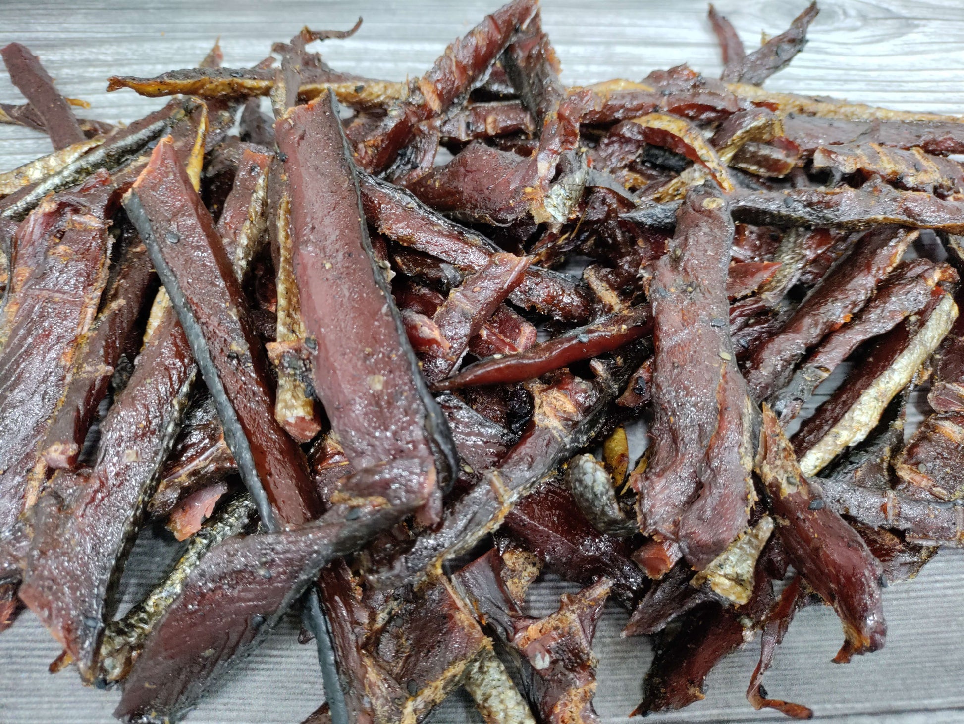 Pile of smoked wild sockeye salmon jerky strips on a wooden board.