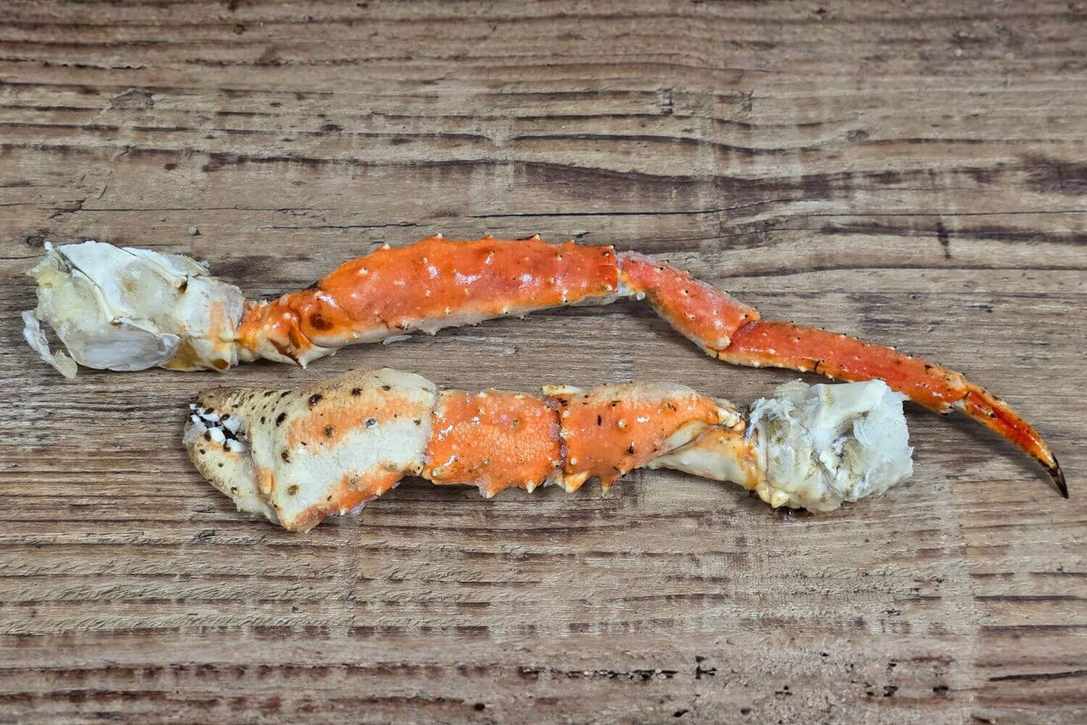 Wild Alaskan red king crab leg and claw sections arranged on a rustic wood surface