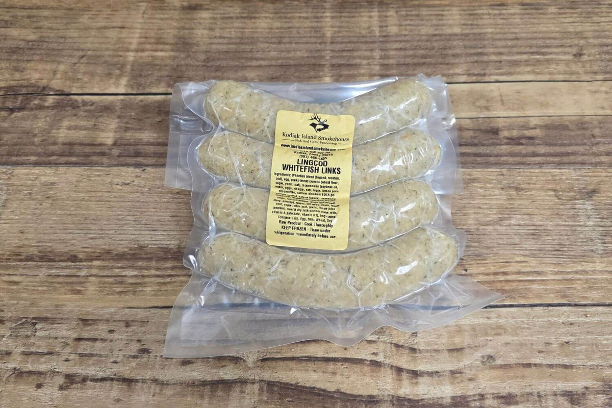 Vacuum-sealed package of wild Alaskan lingcod whitefish sausage links in natural hog casings with Kodiak Island Smokehouse label, on rustic wood.