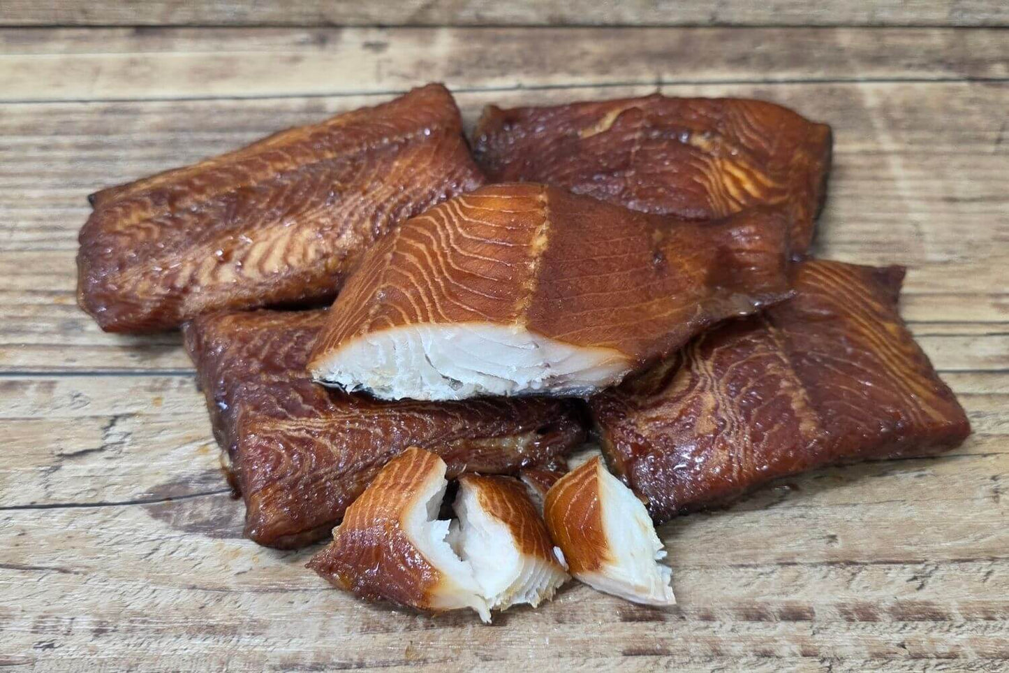 Maple Miso Smoked Black Cod with a dark caramelized exterior and buttery white flakes displayed on a rustic wooden surface.