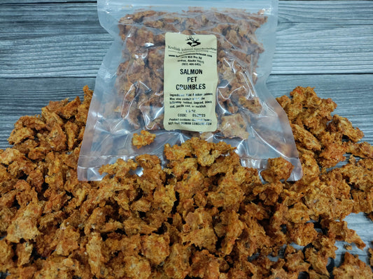 Dehydrated wild Alaskan salmon pet crumbles spilled around a clear resealable bag.