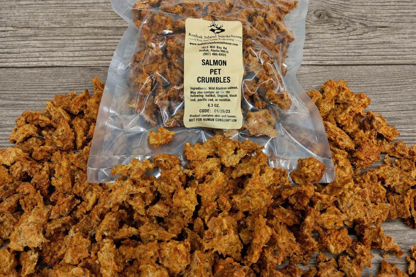 Dehydrated wild Alaskan salmon pet crumbles spilled around a clear resealable bag.