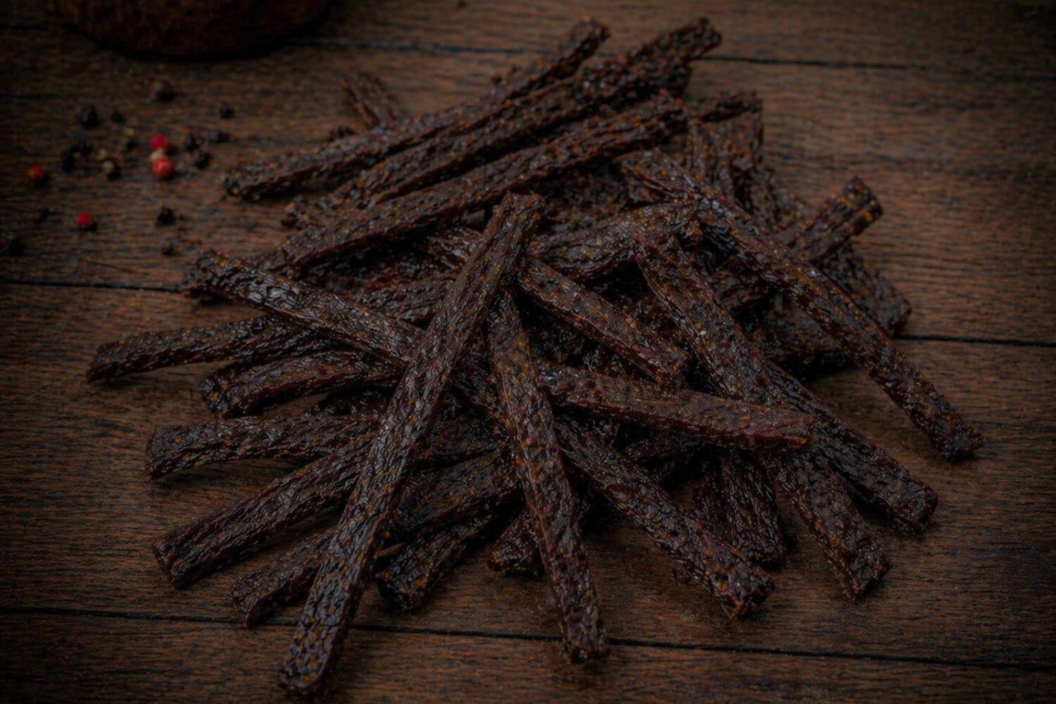 Smoked wild game ground jerky strips arranged in a loose pile showing thin, formed texture
