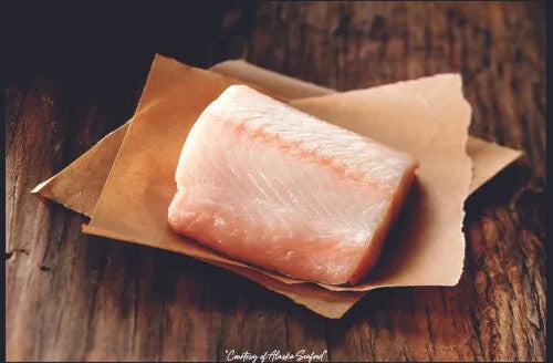 Raw Black Cod portion on parchment paper, photographed in rustic Alaska-inspired style.