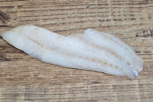 Skinless rockfish fillet on rustic wood surface.