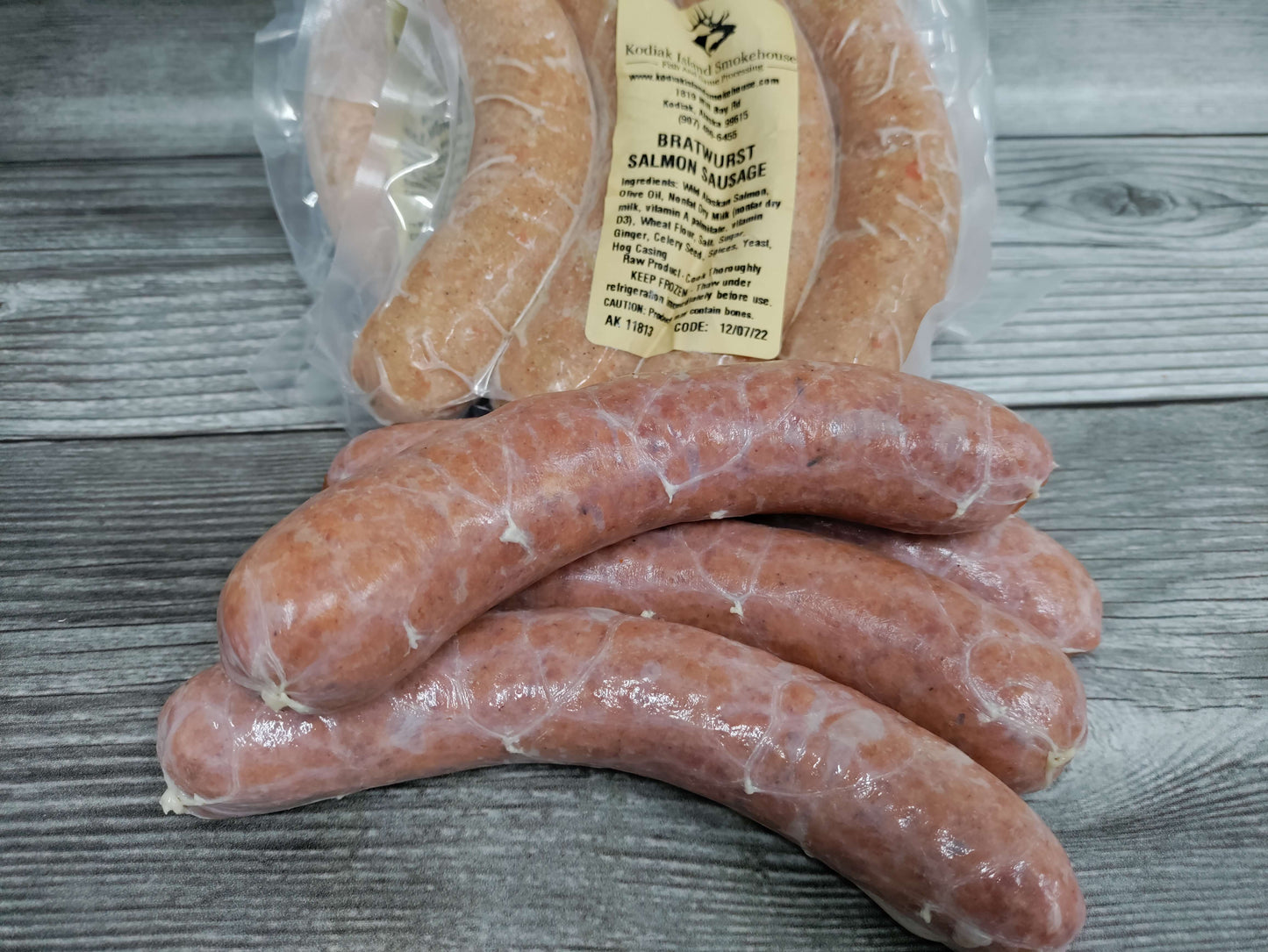Vacuum-sealed salmon sausage links arranged on a rustic wooden surface.