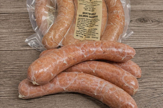 Vacuum-sealed salmon sausage links arranged on a rustic wooden surface.