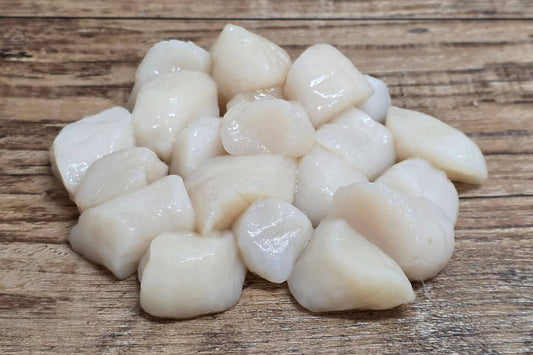 Raw Wild Alaskan Weathervane scallops arranged on a rustic wood surface.