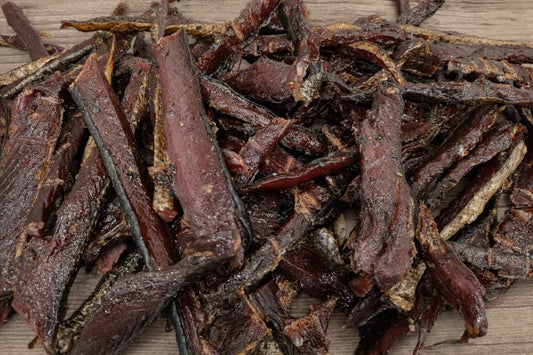 Pile of smoked wild sockeye salmon jerky strips on a wooden board.