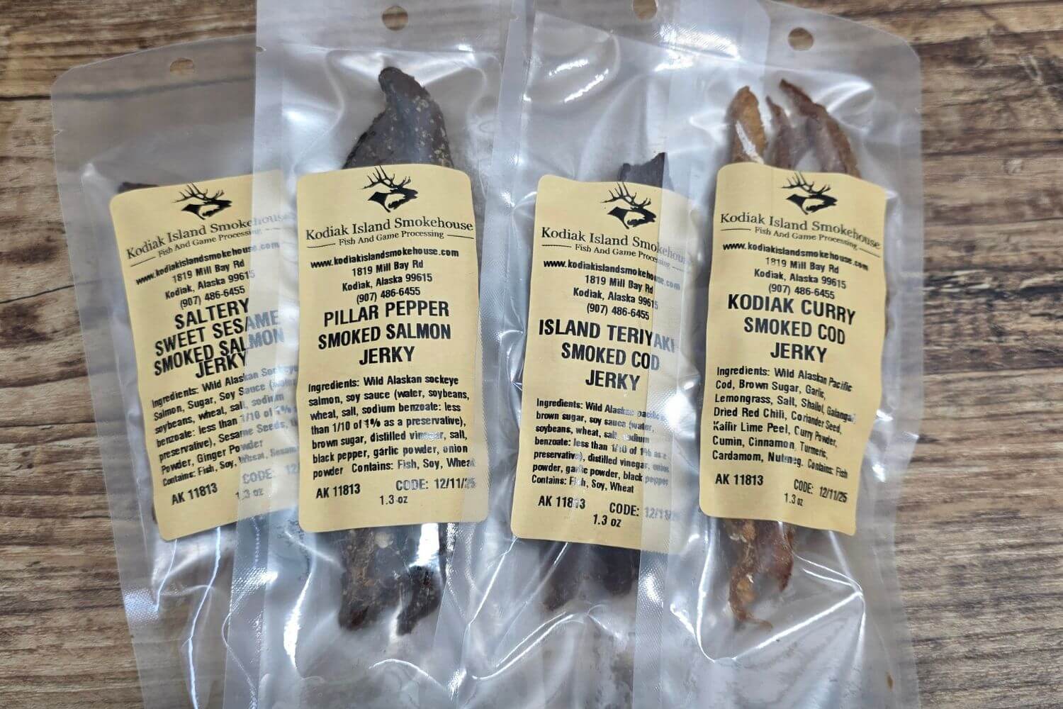 Four vacuum-sealed bags of assorted wild Alaskan smoked fish jerky sampler flavors.