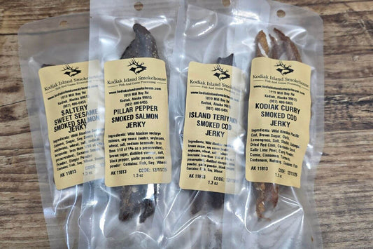 Four vacuum-sealed bags of assorted wild Alaskan smoked fish jerky sampler flavors.